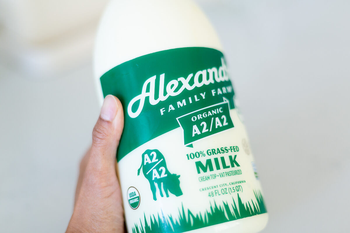 Hand holding a bottle of Alexandre Family Farm A2/A2 milk, focusing on label details. (Photo Credit: Vivian Keithley)