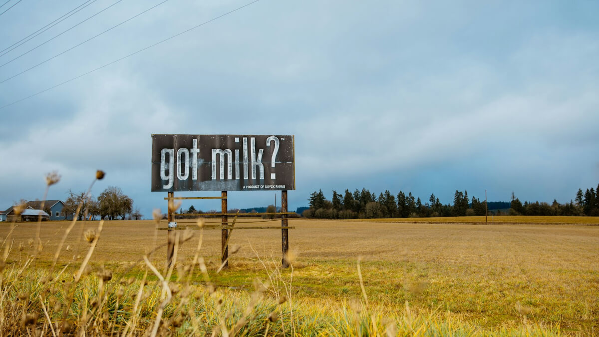 A rustic billboard in a rural field reading ‘got milk?’ under a cloudy sky. (Photo Credit: Christopher Ott)