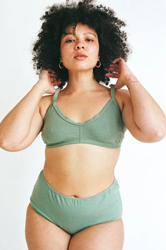 A woman with curly hair wearing the Pansy Smile Bra and panties in the color Mermaid